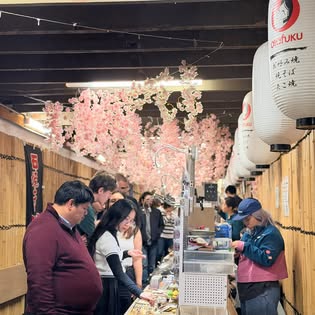 The lantern-strung laneway with people browsing stalls